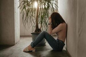 mujer sentada depresión parada junto a la ventana y ansiedad foto
