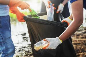 volunteer woman picking up garbage plastic for cleaning at river park photo