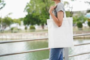 hipster woman holding white tote bag for mock up blank template photo