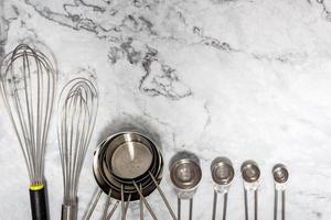 Cooking tools concept on marble tabletop with whisk, measuring cups, measuring spoons represent follow proportion of the recipe make food taste good. photo