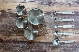 Set of measuring cups and measuring spoon with a handle made from stainless on wooden tabletop in top view photo
