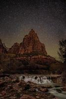 fotografía de lapso de tiempo del río con vistas a la montaña de roca en la noche foto