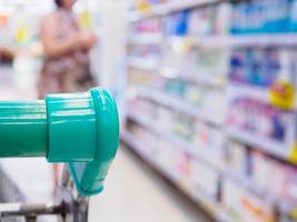 closeup shopping cart handle with customer in supermarket background photo