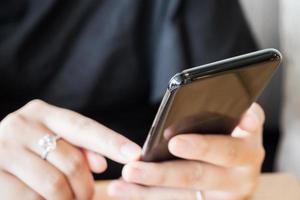 mujer con anillo de diamantes en la mano usando un teléfono inteligente en un café restaurante foto