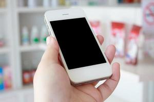 hand holding smart phone in drugstore photo