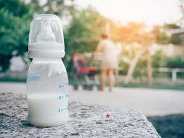 baby milk bottle on stone table over Mother with baby carriage background photo