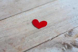 Red paper with heart shape on grunge wooden background photo