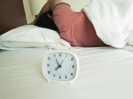 white alarm clock and sleeping man photo