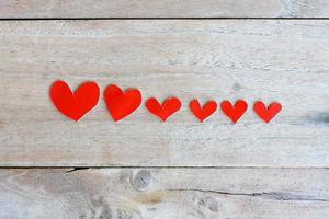 Red paper with heart shape on grunge wooden background photo