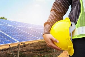 Young business man engineer hold yellow helmet at solar panel power plant construction site background photo