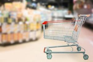 Empty red shopping cart with Abstract supermarket grocery store blurred defocused background with bokeh light photo