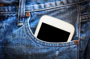 teléfono móvil en el bolsillo de los jeans con pantalla negra foto