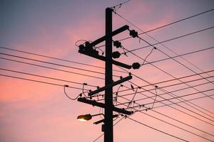 The silhouette of the electric pole with beautiful sunset. This pole used to support overhead power lines and various other public utilities. photo