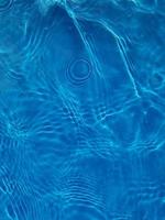 Defocus blurred transparent blue colored clear calm water surface texture with splashes and bubbles. Trendy abstract nature background. Water waves in sunlight. photo