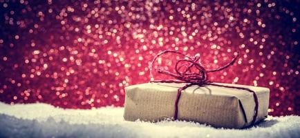 Retro rustic Christmas gift, present in snow on glitter background photo