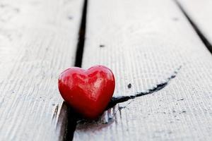 corazón rojo en la grieta del tablón de madera. símbolo de amor foto