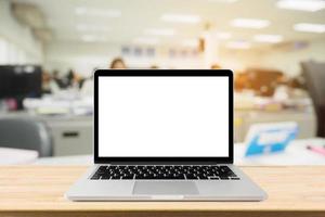 portátil con pantalla en blanco en la mesa de escritorio con fondo interior de oficina borroso foto