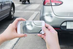 mano usando un teléfono inteligente móvil tomando una foto del daño del accidente automovilístico para el seguro