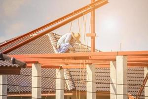 welder workers installing steel frame structure of the house roof at building construction site photo