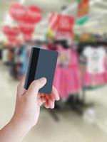 hand holding credit card with clothing store blurred background photo