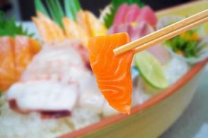 salmon in chopsticks with japanese sashimi set on boat plate photo