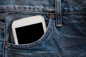 teléfono móvil en el bolsillo de los jeans con pantalla negra foto