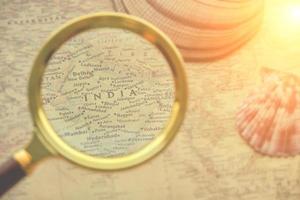 We view India with magnifying glass on retro map.Planning your vacation and travel.Bright sunlight. photo