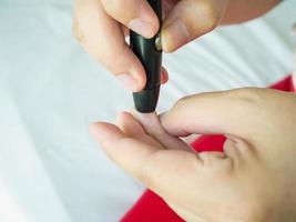 mujer usando lanceta en el dedo, prueba de diabetes foto