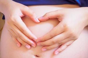 Hands forming heart on pregnancy woman belly photo