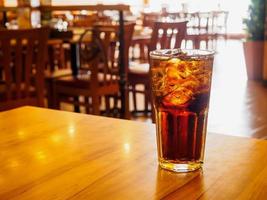 Cola glass with ice on wood table in restaurant background photo