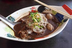 Hot and Spicy Nam Tok noodles soup with meat balls photo