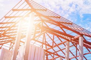 Steel roof frame structure of building house at construction site with blue sky and clouds photo