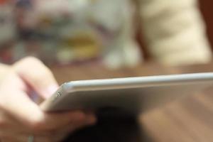 closeup woman hands using tablet computer on wooden table photo