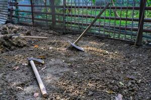 A close up shot of gardening tools in the backyard an axe, a spade etc.