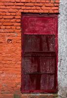 un primer plano de una pared de ladrillo rojo-naranja con puerta de metal. esquema de bloque de color.