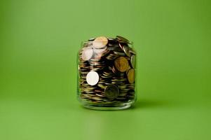 Savings money collected in a glass jar on green background, money saving concept. photo