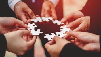 Close-up of a businessman with puzzle pieces in his hands arranged together. teamwork unity in teamwork The concept of combining physical strength and power at work. photo