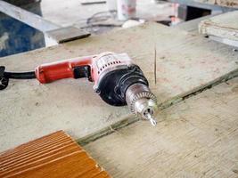 Close up electric drill at work site on wooden board photo