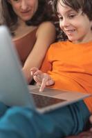 a woman with a child is sitting at a laptop photo