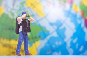 Miniature People Traveler with backpack on The Globe background photo