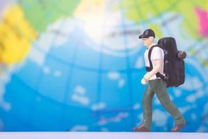 viajero de personas en miniatura con mochila en el fondo del globo foto