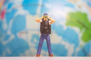 Miniature People Traveler with backpack on The Globe background photo