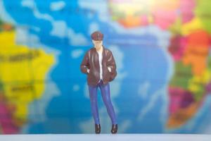 Miniature People Traveler with backpack on The Globe background photo