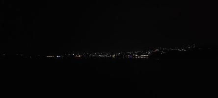 vista de la ciudad de noche oscura desde la montaña foto