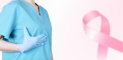 A female doctor in a medical uniform supports her breasts and a pink ribbon as a symbol of breast cancer awareness. Medical pink background. Poster. copy space. photo
