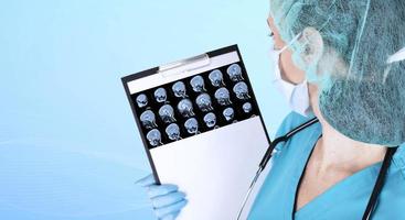 A doctor in medical clothes and blue medical gloves examines a set of MRI scans of a child's brain in a laboratory. Copy space. photo