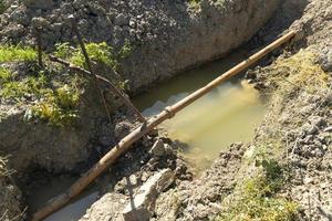 Old rusty metal pipes in a pit with water, water supply system in a mountainous area. Breakthrough of a rusty pipeline. photo
