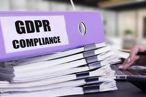 Business documents, folders on an office table with a laptop and a woman's hand. GDPR, General Data Protection Regulation, Privacy, EU Compliance. photo