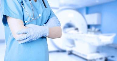 Doctor radiologist in a medical uniform against the background of an MRI computer tomograph in the office. Soft blurred toned background. photo