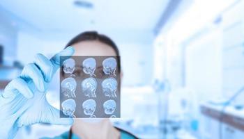 Beautiful woman doctor radiologist, oncologist looks at MRI images of a child. Soft blurred clinic background. photo